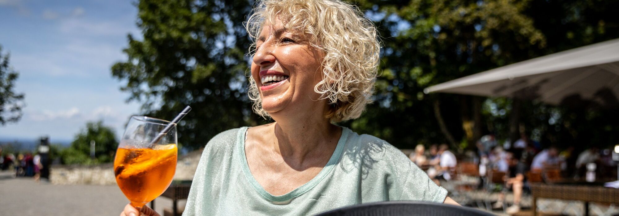 Frau mit Aperol Spritz und Bowl, genießt die Sonne