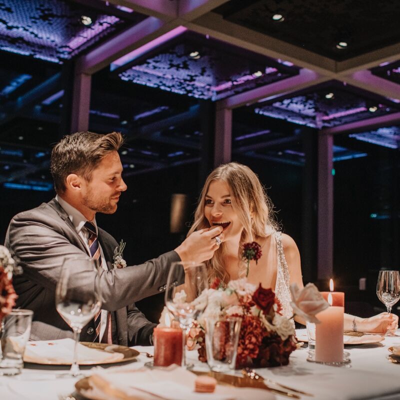 Brautpaar sitzt an einem eingedeckten Tisch im Glaskubs